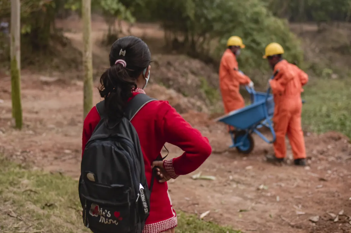 A girl watches a cleanup crew remove lead- contaminated soil in Labanchora, Bangladesh.