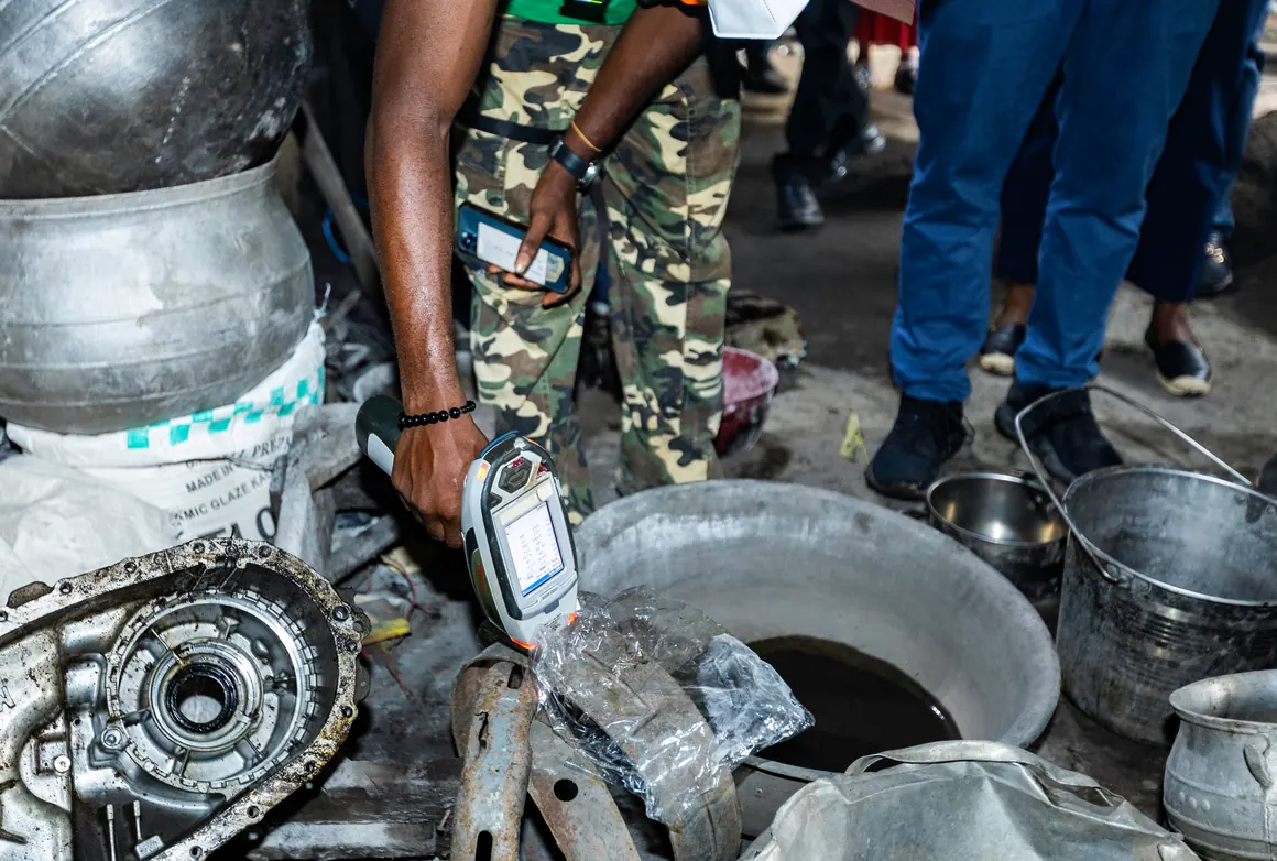 A researcher in Ghana tests metal cookware for lead with an XRF analyzer.