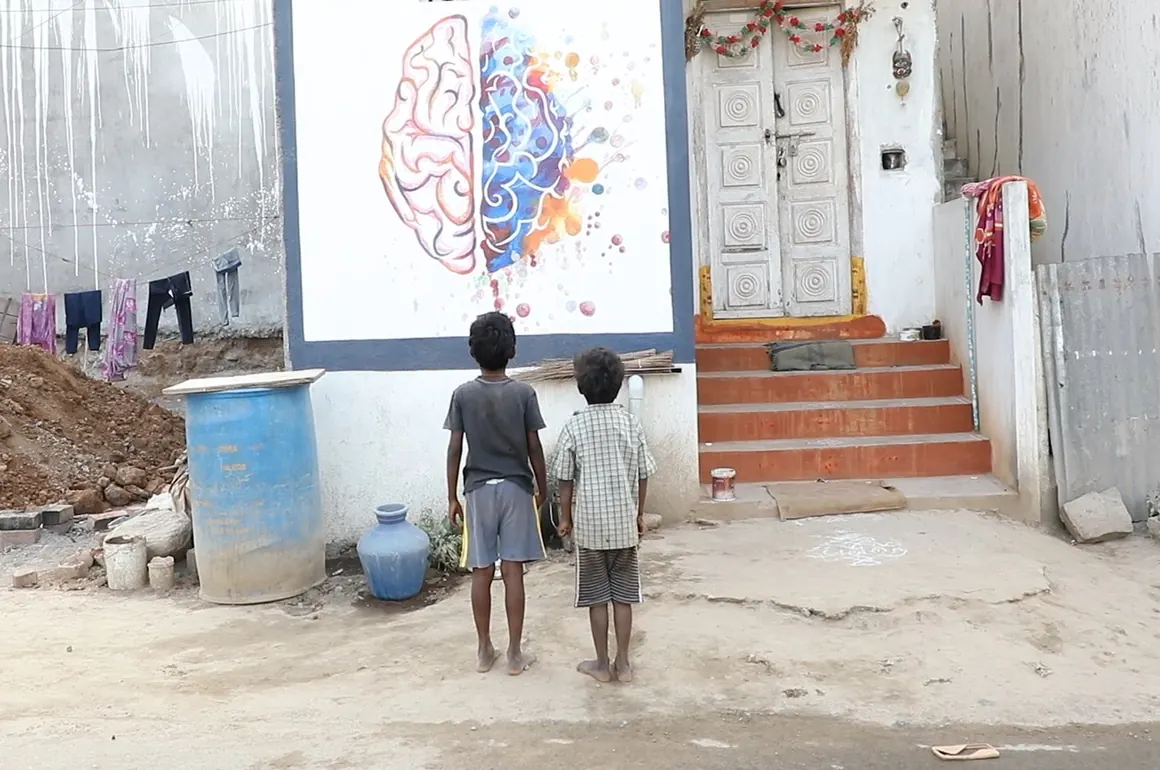 Children in India look at a mural showing how lead harms the developing brain.