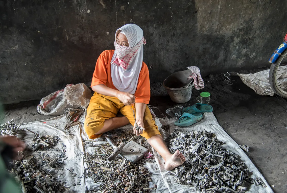 A woman extracts lead from used batteries in Pesarean, Indonesia.